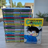 Stack of 'Conan' manga books with a single book cover displayed in front on a wooden surface.