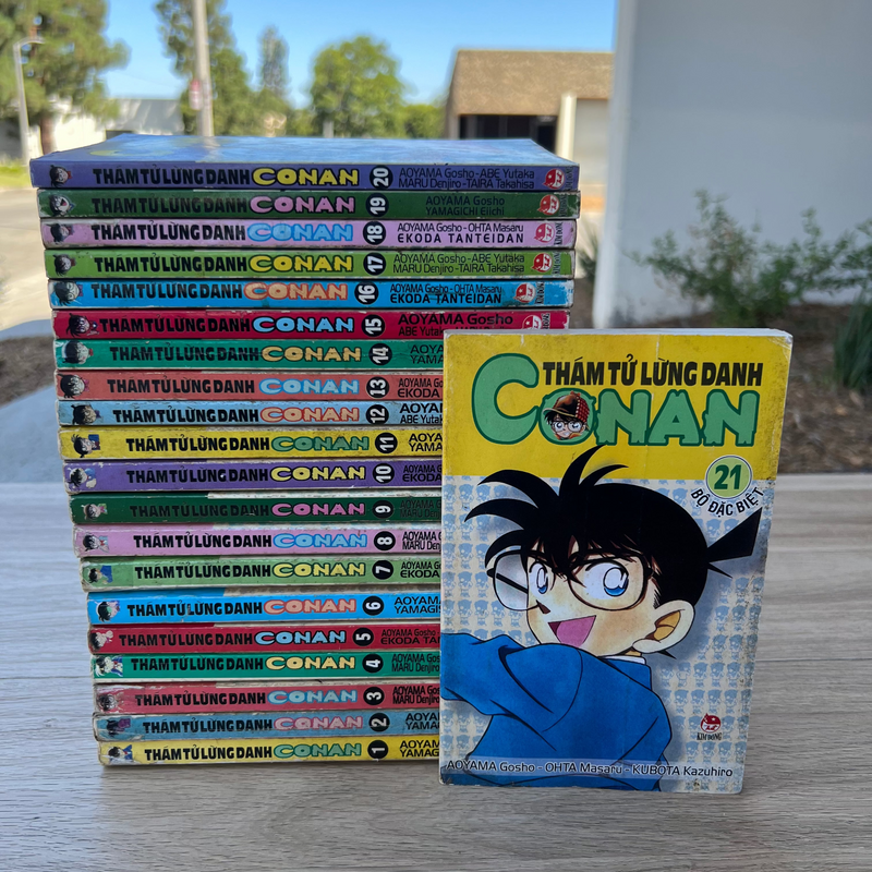 Stack of 'Conan' manga books with a single book cover displayed in front on a wooden surface.